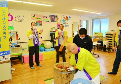 写真:黄色い法被姿の会員のかけ声とともに餅をつく利用者