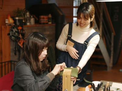 写真:革小物教室「Bouvardia Leather Works」で参加者を指導するあなだちはるさん(右)=大津市