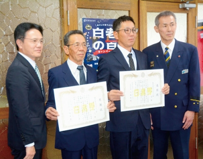 写真:感謝状を受けた秀己さん(中央左)と表彰状を授与された忍さん(同右)