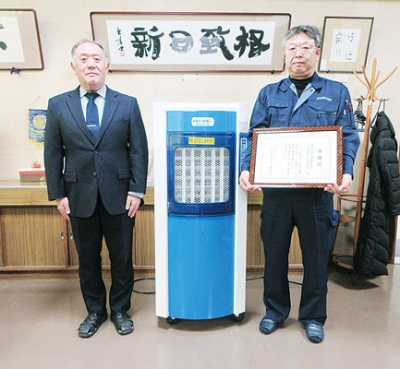 写真:寄贈した気化式冷風機の前で感謝状を手にする望月社長