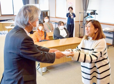写真:長谷川会長(左)から見舞金を受け取る出席者