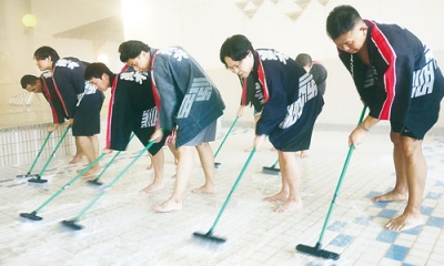 写真:床のタイルを丁寧に磨く従業員ら