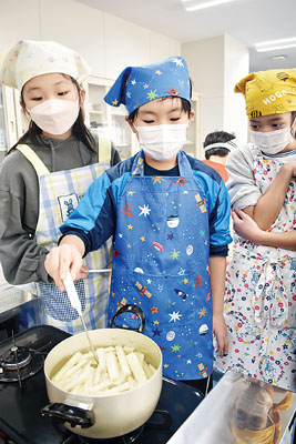 写真:温度計で適温を保ち、ビートから糖分を抽出する児童たち