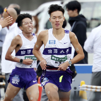 写真:全日本大学駅伝で駒大の6区・村上響(左)からたすきを受け取った佐藤圭汰=11月、津市