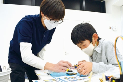 写真:スタッフの助言を受けながら4足歩行ロボットを組み立てる参加者