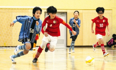 写真:【MRC FC-北湘南サッカースクールホワイト】競り合う両チームの選手たち=登別市総合体育館