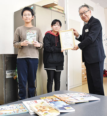 写真:東小児童代表に図書を届ける川上参事(右)