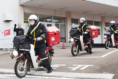 写真:年賀状をバイクに積んで出発する配達員ら=1日、室蘭郵便局