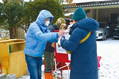 写真:参拝者に焼き芋を手渡す諸岡さん