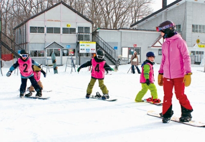 写真:ゲレンデでインストラクターから指導を受ける参加者たち