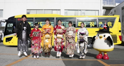 写真:「はとバス二十歳を祝う会」で、記念写真に納まる20歳になるガイドの女性と整備士の男性=6日午前、東京都大田区