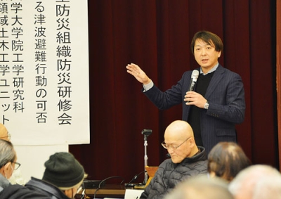 写真:車避難のアンケート結果や課題について講演する有村教授