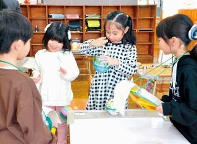 写真:在校生が作ったおもちゃで遊ぶ体験入学の子どもたち(左から2人目と3人目)