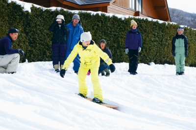 写真:上手に雪板に乗り滑り降りる子ども