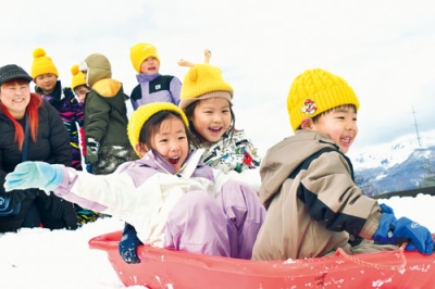 写真:職員が作った雪の坂でそり滑りを楽しむ園児たち
