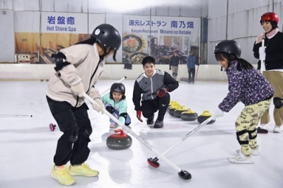 写真:カーリング体験会に参加した子どもたちと上地雄大さん(中央)=2025年11月、沖縄県南風原町