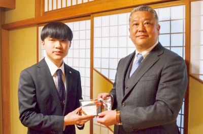 写真:奨学生の橋本さん(左)に記念品を贈る松本副会長