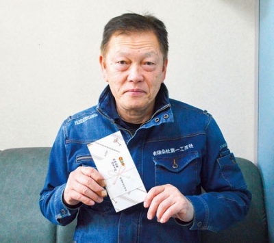 写真:会員に配布する商品券を手にする山田会長