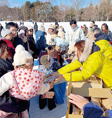 写真:伊達飲食店組合の菓子の配布に集まる雪まつり来場者ら(提供写真)