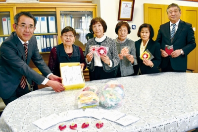 写真:交通安全のお守りと毛糸のたわしを贈る手芸クラブのメンバーら