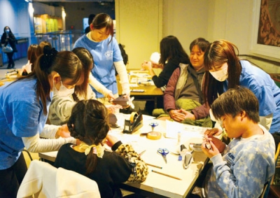 写真:来場者にペーパークラフトの作り方を教える学生たち
