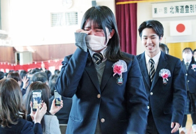 写真:保護者らに見守られ学びやを後にする卒業生