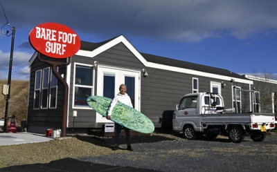 写真:「ベアフットサーフ」の前に立つ越後一雄さん=2025年12月、宮城県亘理町