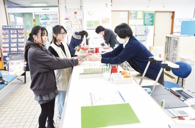 写真:募金活動で集めた善意を日本ユニセフ協会の口座に振り込む児童(左)