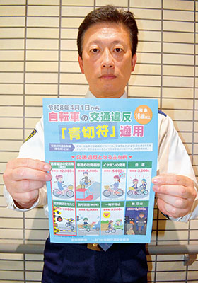 写真:自転車の青切符制度を周知するチラシを手にする室蘭署員