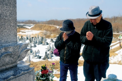 写真:墓前で手を合わせる市民=17日午前10時45分、室蘭市望洋台霊園