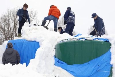 写真:雪山からタンクを掘り出す高砂酒造の社員ら=19日午前、美瑛町