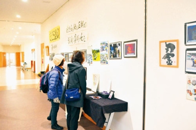 写真:「たたらの会」の活動を紹介する写真に見入る来場者